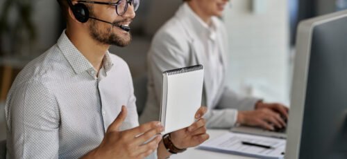 Happy customer service representative using computer and having video call with clients while working at call center.